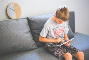 Child sitting on sofa with tablet
